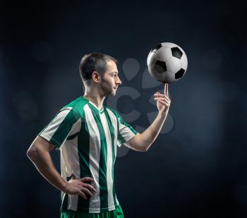 Football-player spinning soccer ball over black background