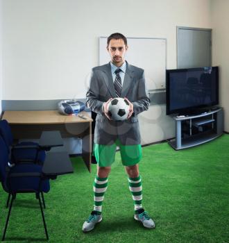 Businessman in sportwear holds a ball standing in the office