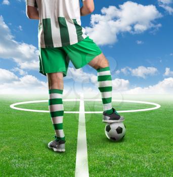 Football player with a ball between his legs standing on the  football ground