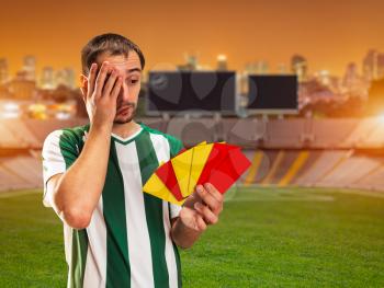 Football player holds red and yellow cards standing on the football ground