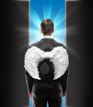 Businessman with wings on his back standing in front of the door 