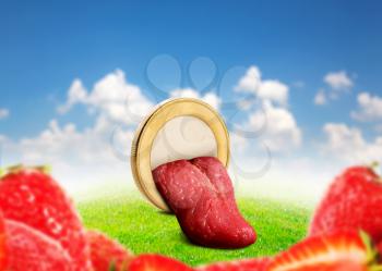 Human tongue in the coin among strawberries on the meadow