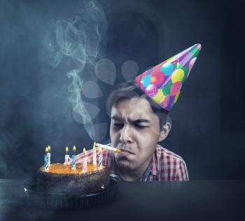 Sad birthday boy smoking in an abandoned room with cake
