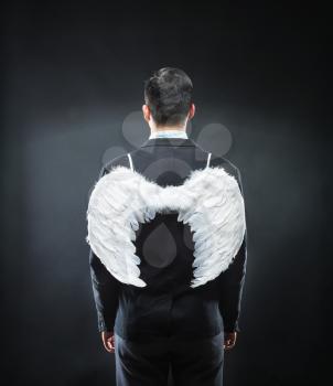 Businessman with wings is standing back