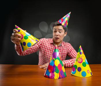 Young man playing with Birthday hats at the table