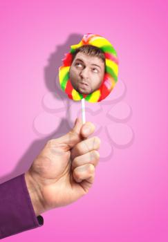 Male hand holding a lollipop with male face in it