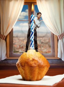 Man stands on birthday cake with a candle