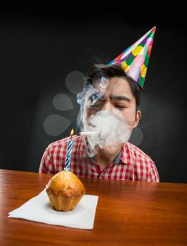 Sad birthday boy is smoking at his cupcake