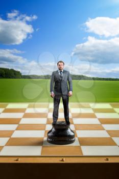 Businessman standing on the chess board like a king