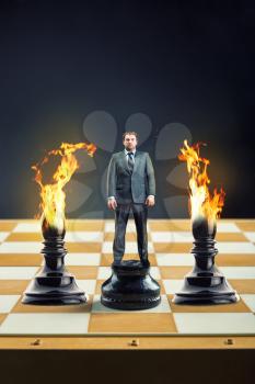 Businessman standing on the chess board instead of a pawn between two blames