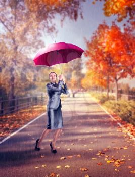 Woman with umbrella while raining on the autumn street