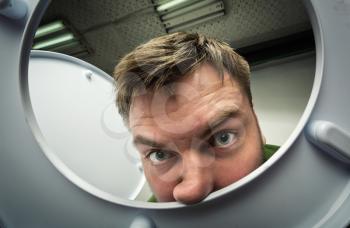 Bizarre man in the bathroom looking in the toilet bowl