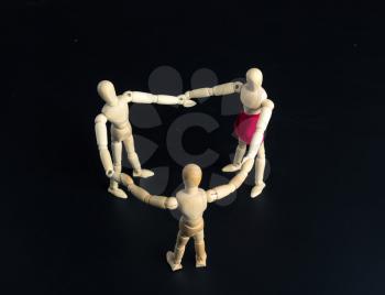Family of wooden figures standing in circle over dark background