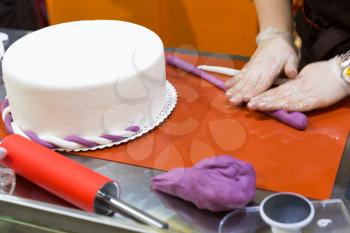 Baker hands decorating cake with gum paste