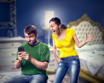 Excited man and woman playing with phone in the bedroom