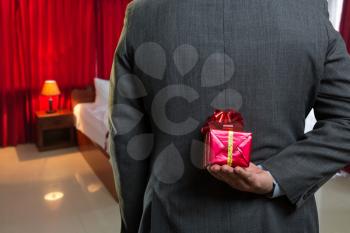 Businessman hiding a gift behind his back closeup