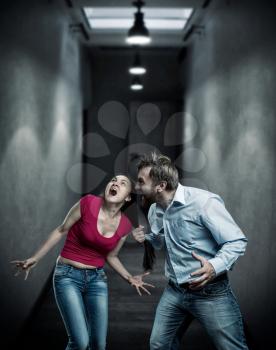Man and woman fighting in dark corridor