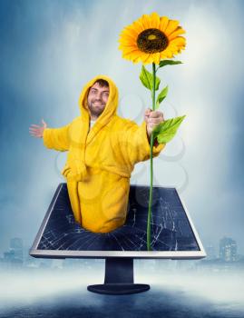 Happy man in yellow bathrobe holding sunflower in the computer monitir