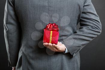 Businessman hiding a gift behind his back