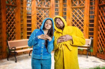 Pensive woman in blue pijamas and man in yellow bathrobe in the room