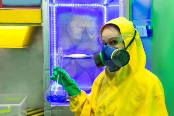 Woman wearing protective outerwear suit in chemical laboratory with flask