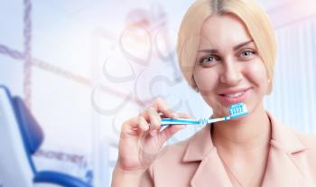 Portrait of smiling woman with tooth brush in dentist's office