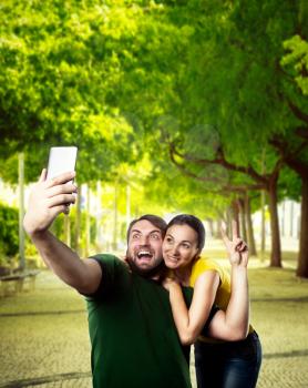 Happy man and woman making selfie in the summer park