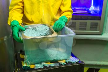 Man in protective outerwear suit sorts crystal meth in packs