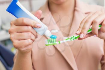 Woman putting toothpaste on the tooth brush closeup