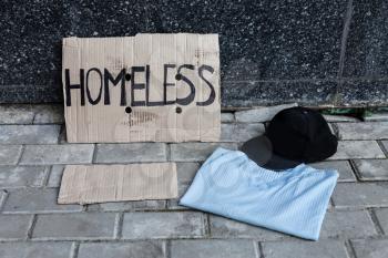 Cardboard for homeless, shirt and cap near the wall in the city