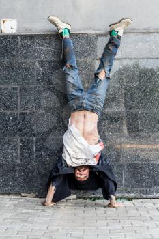 Young vagrant doing handstands on the street