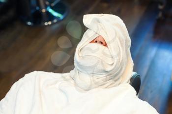 Man in the barber chair twisted in towel
