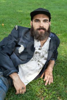 Bearded homeless lying on the lawn