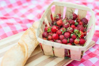 Close up of basket with strawberries, French bread lying next to it