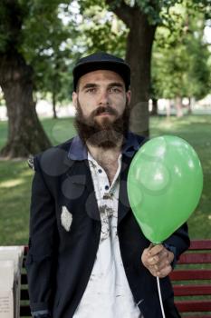 Bearded vagrant with ballon in the park