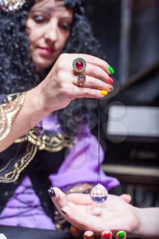 Sorceress reading somebody's hand using magic crystal