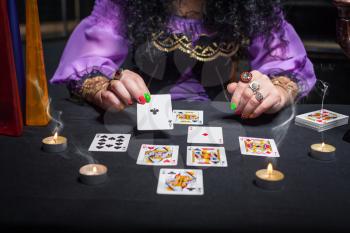 Close up of sorceress telling fortunes using cards and candles