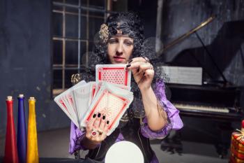 Sorceress practising witchcraft with cards in her room