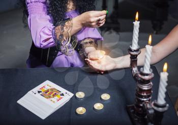 Sorceress reading somebody's hand using magic crystal