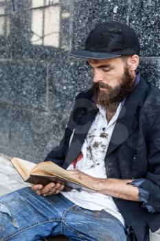 Homeless is reading sitting outdoor