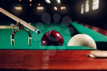 Close up of cue on the stand and billiard balls near the pocket