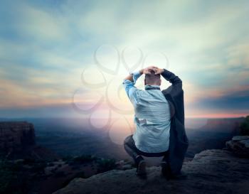 Businessman sitting in despair on the edge of the mountain