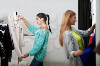 Two young women buyinng dresses in the shop