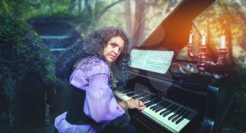 Mystic woman playing the piano in the forest