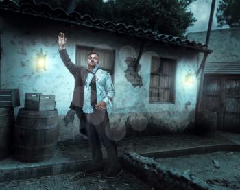 Injured businessman with hand up near an old house