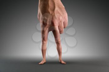 Male hand with legs instead of fingers over grey