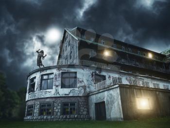 Scary zombie girl on a balcony of the spooky house. Horror. Halloween.