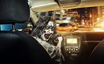 The undead girl with bloody face rides in the car agaist night city on the background. Scary