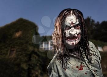Scary zombie girl near the abandoned house. Horror. Halloween