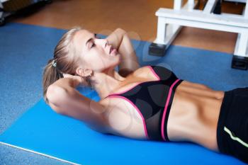 Young girl exercising abs in the gym